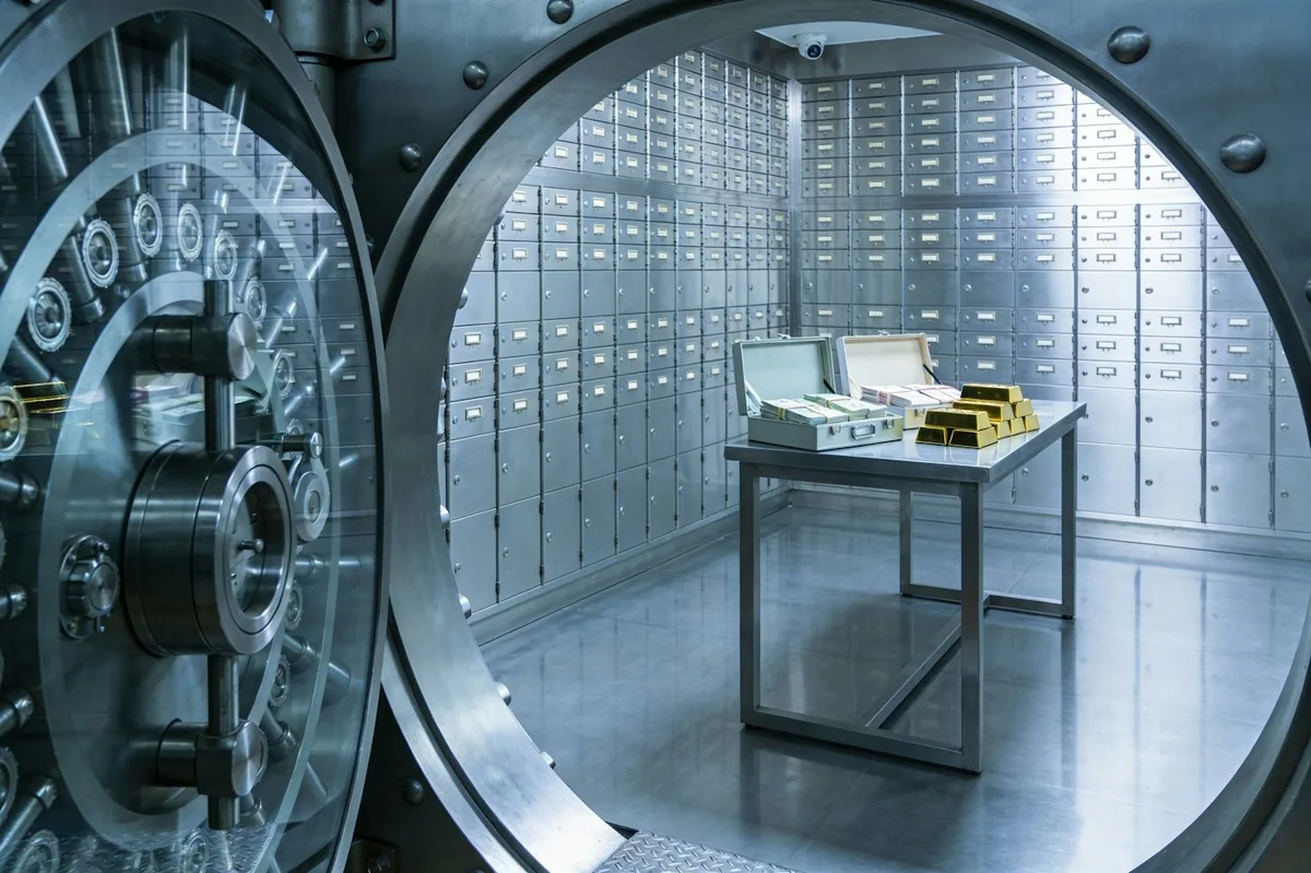 Open steel bank vault door with safe deposit boxes behind it